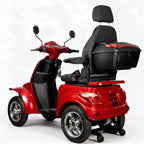 A red and black four-wheel electric mobility scooter with a spacious backrest seat, a large rear storage box, and chrome wheels, shown on a light gray background.