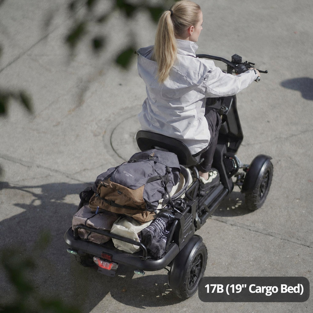 A woman rides a black four-wheeled electric cargo scooter on a concrete surface, viewed from behind. The scooter has a rear cargo bed carrying a gray backpack and other gear.