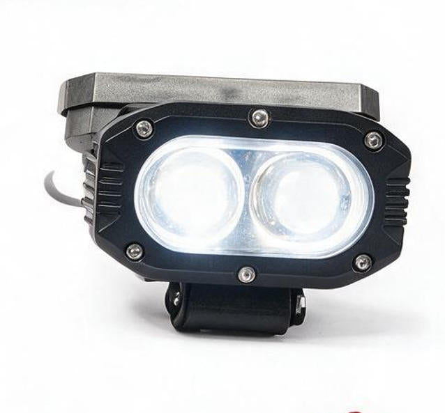 A dual LED off-road vehicle light with a black housing, silver screws, and a gray mounting bracket, shown illuminated on a white background.